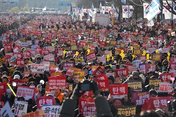 Una multitud corea eslóganes durante una manifestación para exigir la destitución del presidente de Corea del Sur, Yoon Suk Yeol, en el exterior de la Asamblea Nacional, en Seúl, Corea del Sur, el 14 de diciembre de 2024. Los carteles dicen "juicio político". (AP Foto/Lee Jin-man)