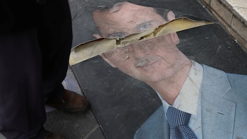 Una persona junto a una foto dañada del presidente sirio Bashar al-Assad en Damasco (REUTERS/Mohamed Azakir)